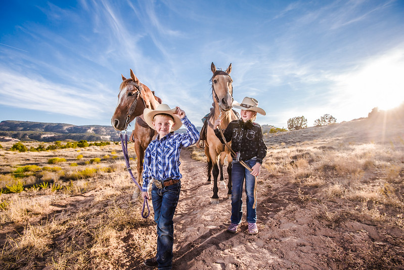 Two boys pulling horses in the desert.