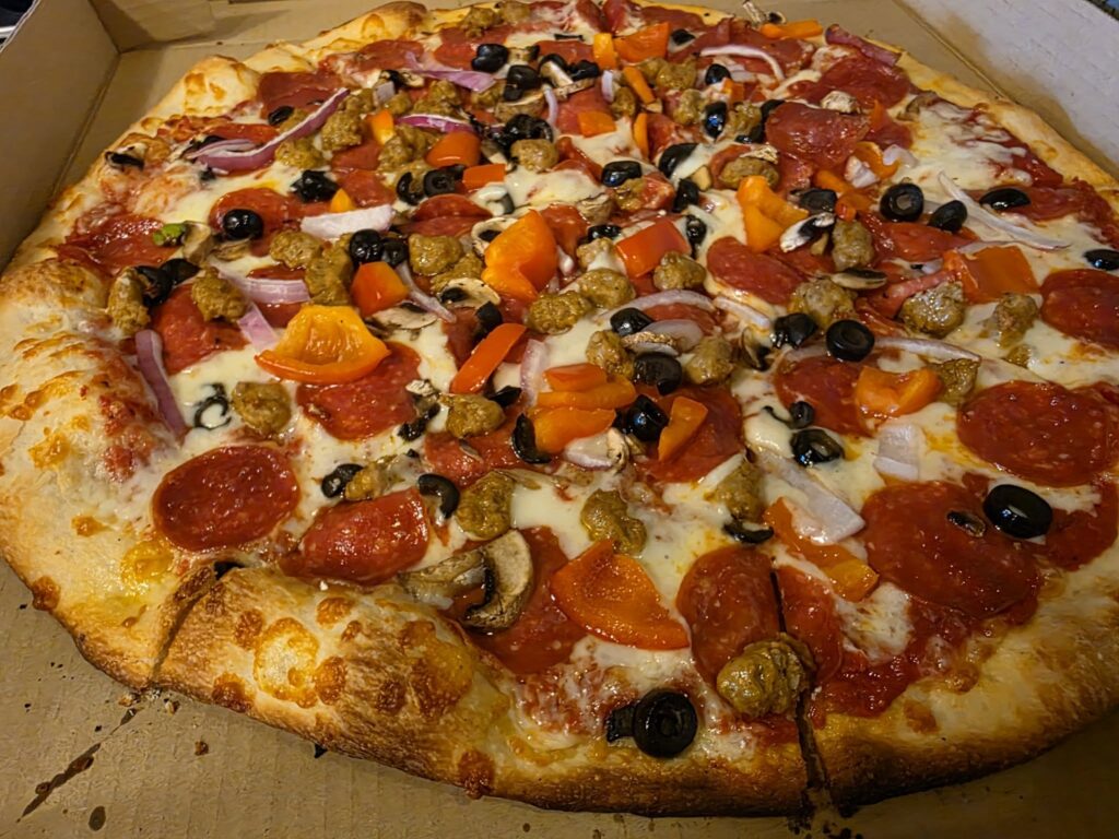 a pizza with cheese, pepperoni, bell peppers and olives