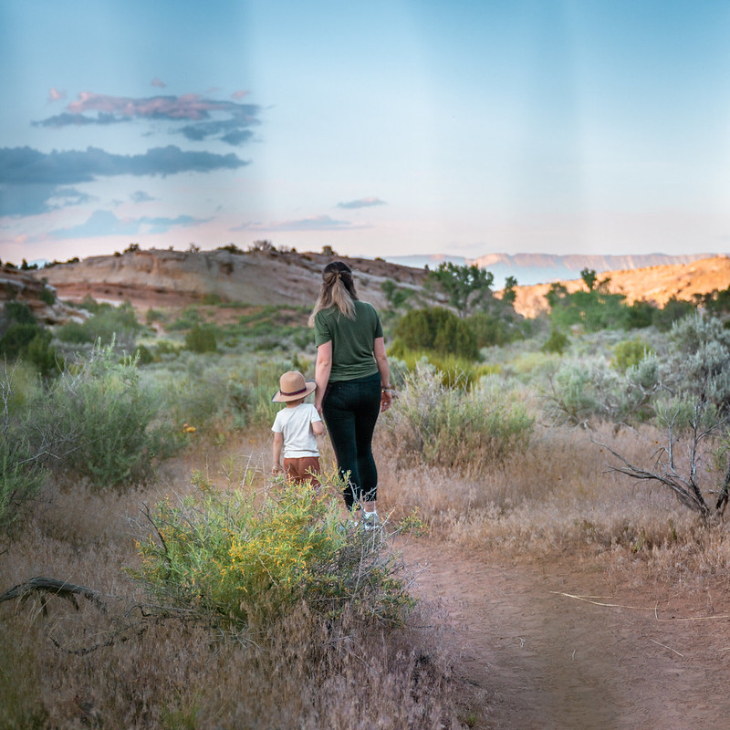 A mom and son walking on a dirt path surrounded by nature in Fruita, CO.
