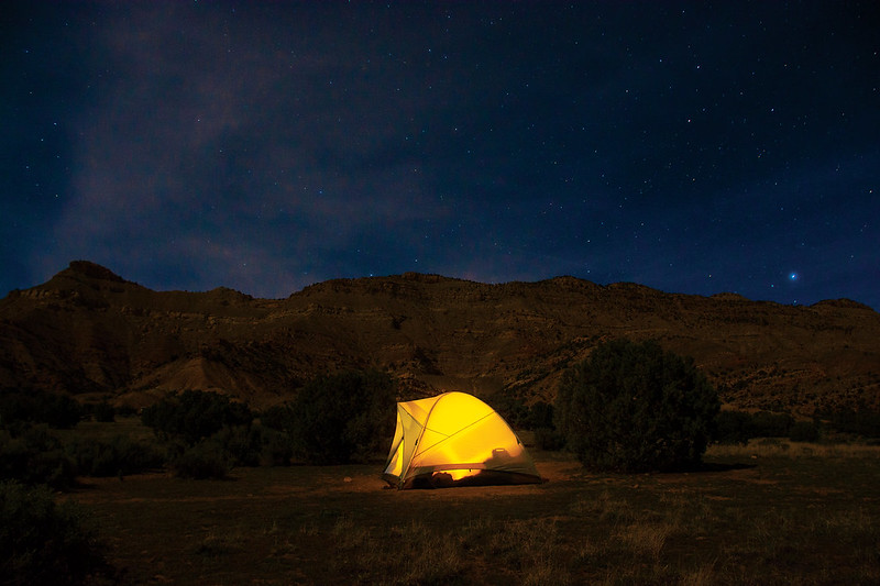 A yellow tent glows from a lantern under the night sky at a campground on 18 Road in Fruita, Colorado.