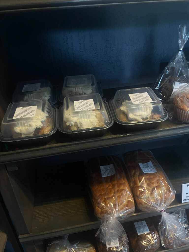 Cinnamon rolls and bread on shelves at Hailie's Oven.