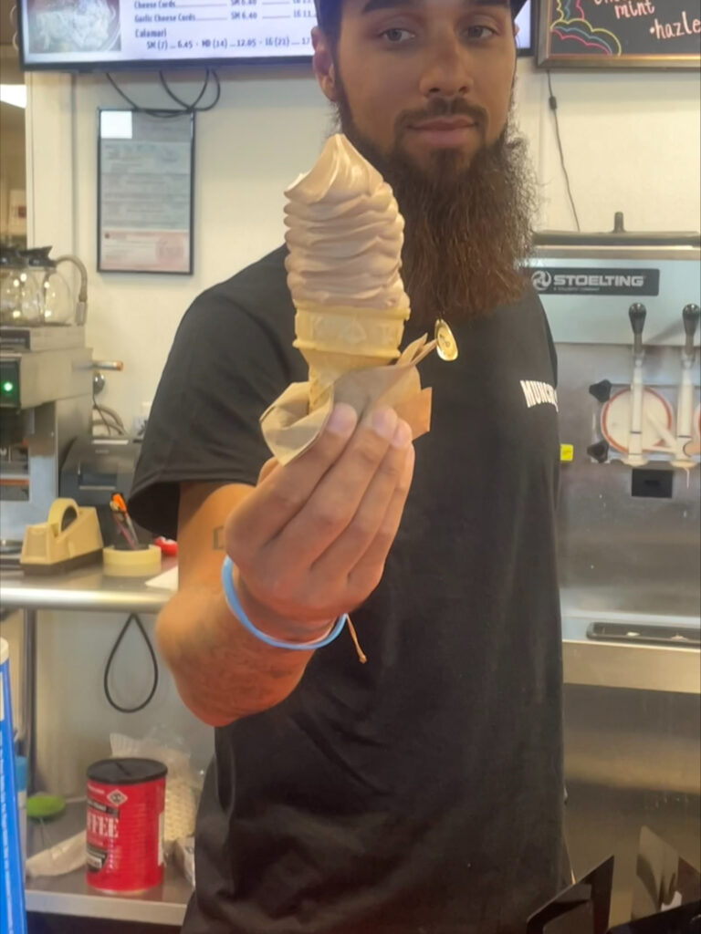 A Munchie's employee hand out an ice cream cone.