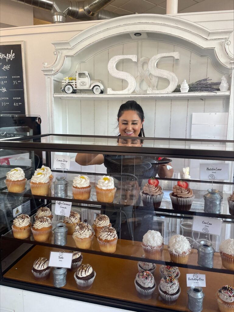 A Sweet & Simple employee smiles while serving cupcakes.