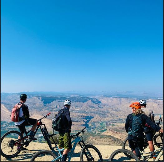 Three bicyclists stop on a hill to take in the views of Fruita.