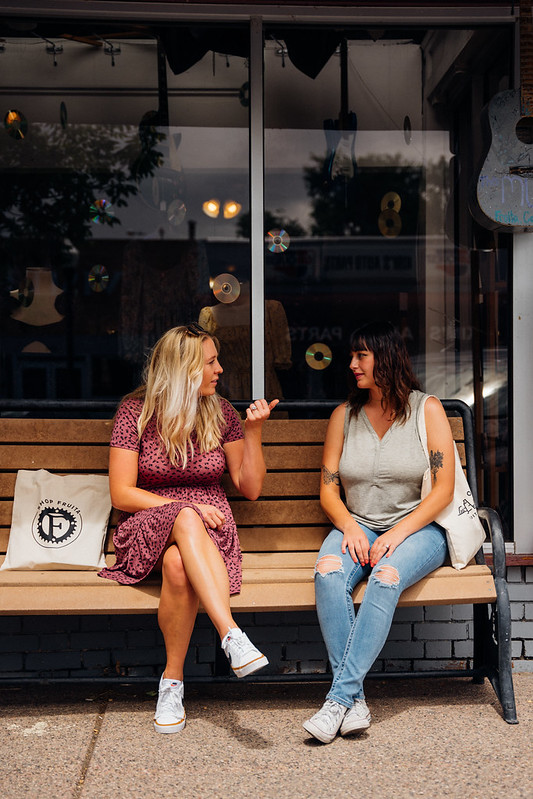 Two women sit on a bench outside of a store in Fruita.