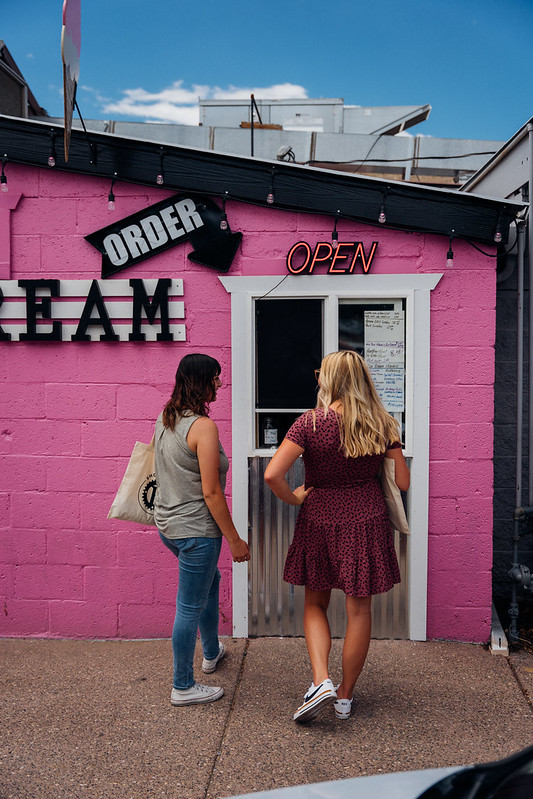 Two women standing at a door waiting to be served.