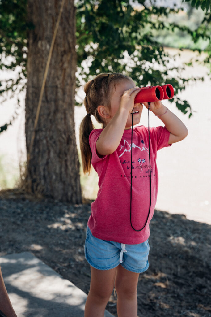 A young girl looks through a pair of binoculars.