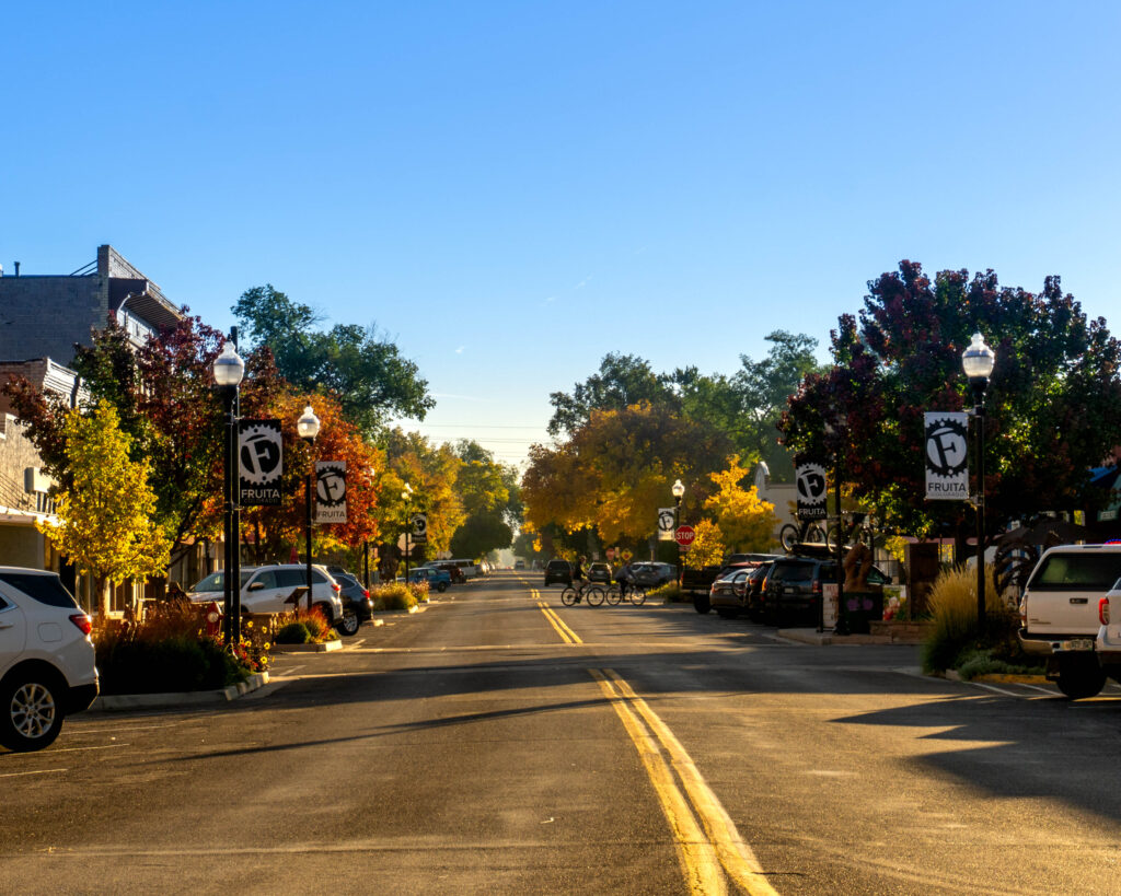 A picture of the street through Downtown Fruita with yellow and red trees on the sides.