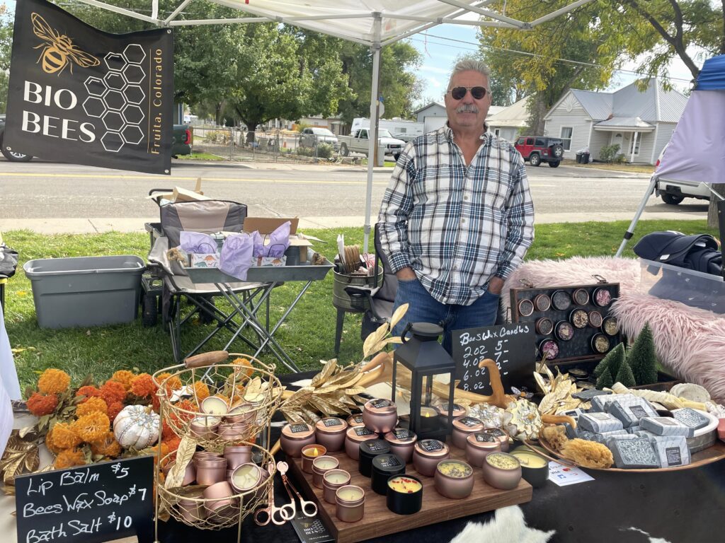 A man poses next to the candles, soap and bath salts his business sells.