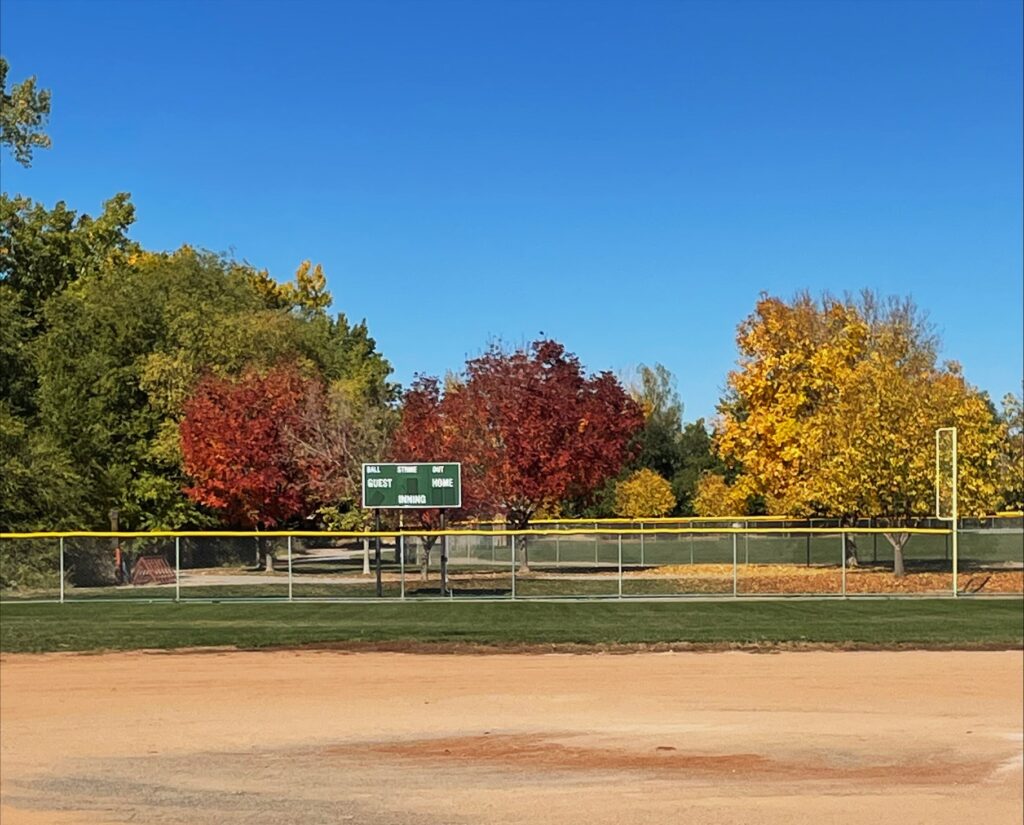 Red, yellow, and green trees around the baseball field at Little Salt Wash Park.