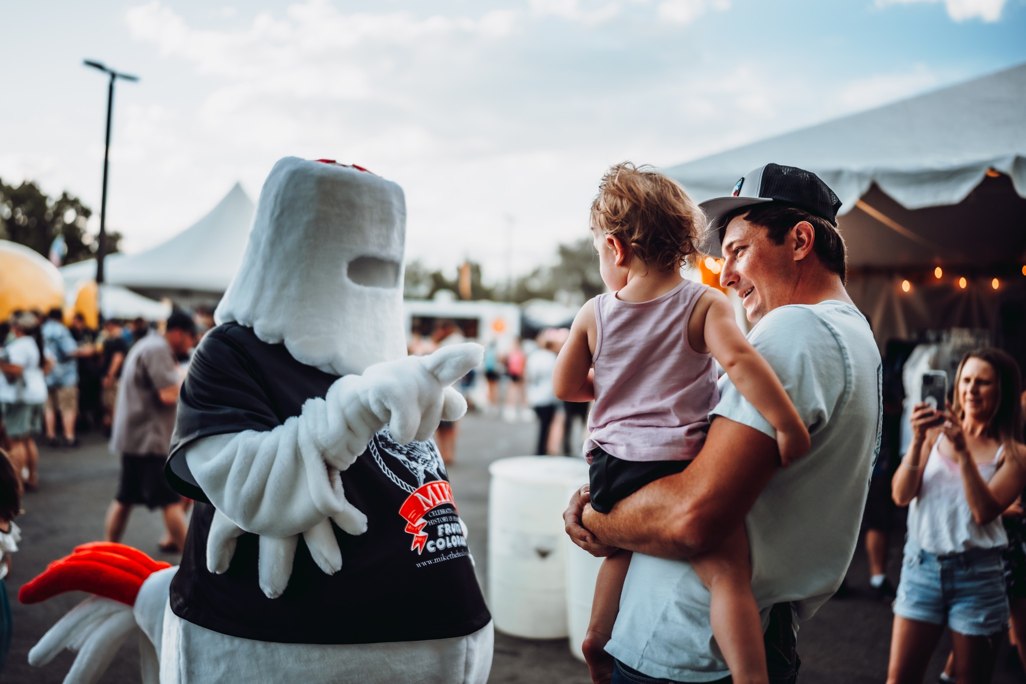 A little girl and her dad visiting with a mascot