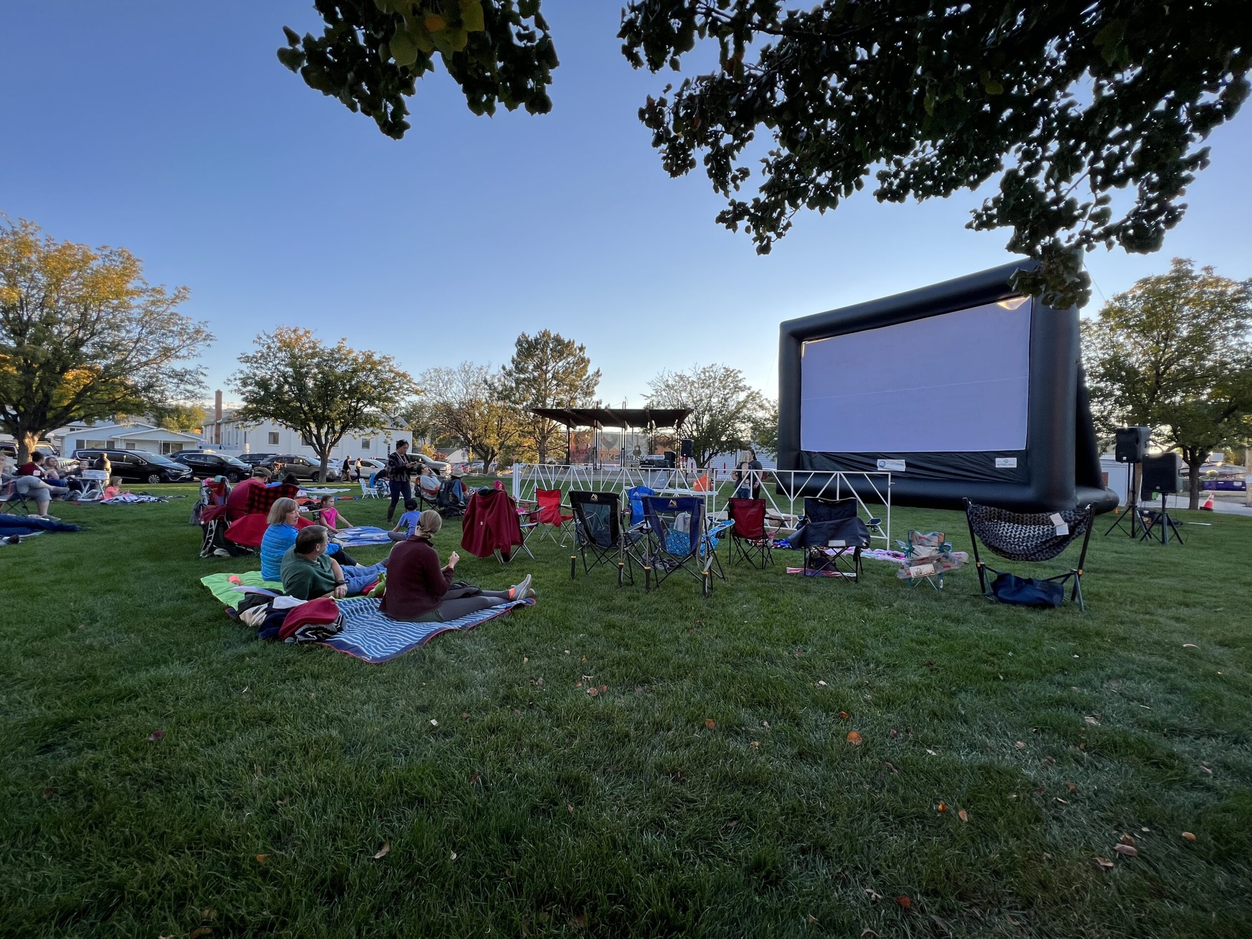 A group of people to watch movies in the park on a blow up screen.