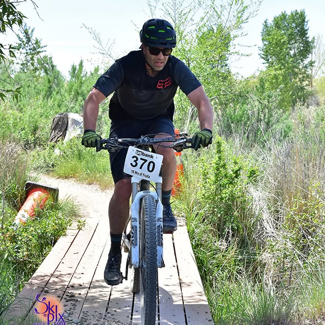 A man rides a bicycle over a bridge.